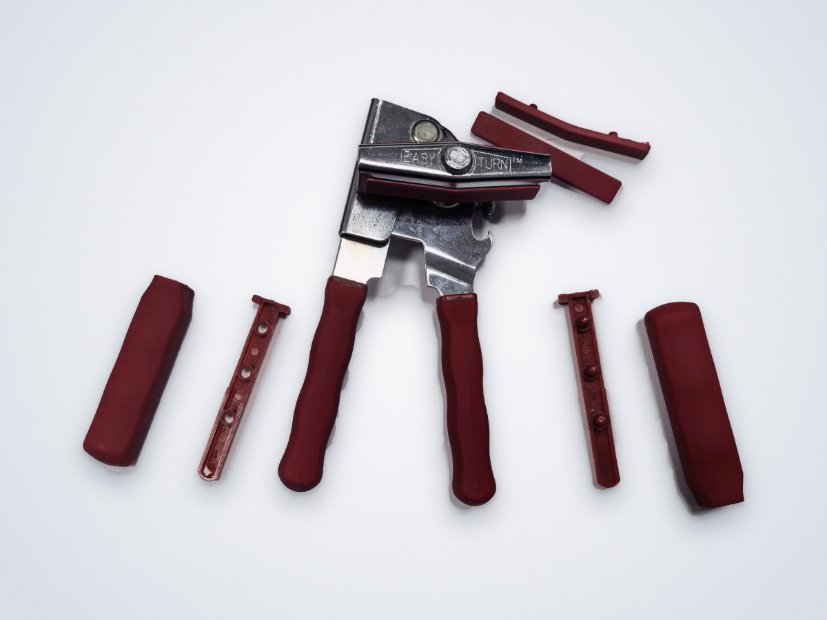 Metal hand tool with red rubber grips and loose grip parts